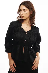 Blusa negra de lino con frunces en el delantero y la espalda, cierre frontal con botones de nácar y mangas 3/4 con puños elásticos.