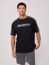 Remera negra de hombre con corte en hombro y manga en color gris, y estampado frontal con el logo de la marca Rusty en blanco con borde gris.