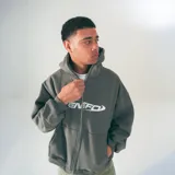 Hoodie gris con cierre frontal, capucha con cordón ajustable, bolsillos tipo canguro y logo "VENEFO" estampado en el pecho.
