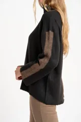 Sweater negro de tejido grueso con cuello alto acanalado. Presenta una franja decorativa en las mangas y el cuello en hilo marrón con brillo (lurex).