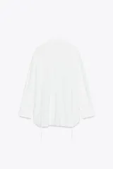 Camisa blanca de corte amplio, con cuello solapa, manga larga y cierre frontal con botones.