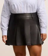 Minifalda negra de cuero sintético con pliegues, cintura alta y cierre con botón y cremallera.