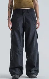 Pantalón cargo negro convertible, con cierre en la parte media de la pierna que permite transformarlo en un short ancho. Presenta bolsillos cargo a los lados y un corte holgado.