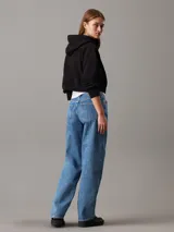 Buzo negro de felpa de algodón regenerativo, corte relaxed boxy, con capucha ajustable con cordón, puños y bajo de canalé e insignia con el monograma de Calvin Klein en el pecho.