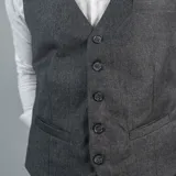 Chaleco de vestir marrón claro con textura de espiga, cuello en V, cierre frontal con botones y bolsillos ribeteados.