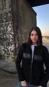 Campera negra de lana con frente de cuero, cierre frontal con cremallera y mangas largas.