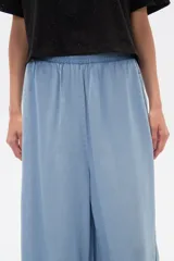 Pantalón capri de denim azul con cintura elástica y aberturas laterales en el ruedo.