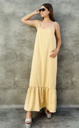 Vestido largo color beige, sin mangas, con tirantes finos y falda con vuelo.