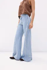 Pantalón jean color beige, de corte recto y tiro alto, con bolsillos delanteros y traseros, y detalle desflecado en los laterales.