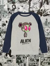 Buzo gris con mangas azul marino y estampado frontal de un personaje alienígena con la leyenda "ALIEN ADVENTURE CLUB".