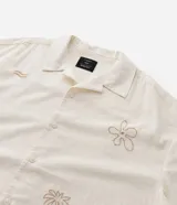 Camisa de hombre con corte boxy, cuello inglés y abotonado delantero. Es de color crema y presenta bordados sutiles de motivos veraniegos en tono naranja claro.