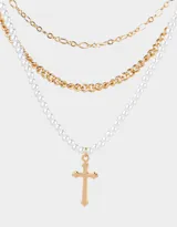 Collar corto de tres capas con cadena de perlas, cadena de eslabones gruesos dorados y cadena fina dorada. El collar de perlas tiene un dije de cruz dorada.