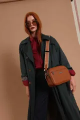 Bandolera color mostaza de simil cuero, con tres cierres principales, cierre delantero y bolsillo trasero. Incluye correa ajustable.