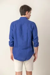 Camisa celeste de lino con cuello clásico y manga larga. Presenta un pequeño logo bordado en el pecho.