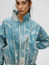 Campera rompevientos estilo biker con capucha desmontable, color celeste con estampado de nubes blancas y detalles en blanco.