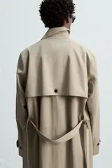 Trench largo regular fit color beige confeccionado en tejido italiano repelente al agua. Tiene cuello con solapas de pico, manga larga con puño ajustable con trabilla, bolsillos de vivo en cadera, bolsillo interior, cinturón del mismo tejido en cintura, bajo con abertura en centro espalda y cierre frontal de botonadura cruzada.