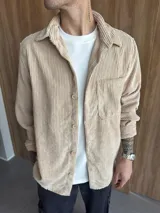 Sobrecamisa color beige de pana con cuello clásico, cierre frontal con botones, manga larga con puños abotonados y bolsillo de parche en el pecho.