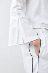 Blusa blanca de lino con escote en V y cierre frontal con lazos. Mangas largas acampanadas.