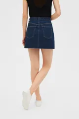 Minifalda de jean color beige con terminación desflecada.