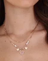 Collar corto dorado con doble cadena, una de eslabones y otra con cuentas y perlas. Incluye dijes de corazones y flores encapsuladas.
