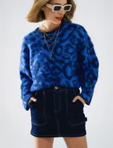 Buzo de lana con cuello redondo, manga larga amplia y corte crop. Presenta un estampado animal print en tonos de azul vibrante.