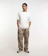 Pantalón cargo paper touch color beige, con bolsillos laterales y cintura elástica ajustable con cordón. Se convierte en bermuda mediante cierres.