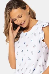 Remera blanca estampada con flores pequeñas en tonos azules y rosados, con mangas cortas con volados. Tejido suave al tacto.