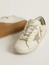 Zapatillas urbanas Golden Goose modelo Super Star, color blanco con detalles en marrón y estrella dorada. Diseño con efecto desgastado y suela de goma.