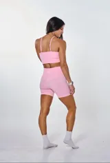 Conjunto deportivo color rosa compuesto por top con breteles finos y logo 'bk.' estampado en blanco, y calzas cortas tipo biker.