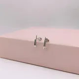 Par de caravanas tipo ear cuff o trepador, hechas en plata 925. Consisten en dos barras delgadas y paralelas que se extienden verticalmente a lo largo del lóbulo, con un diseño curvo en la parte inferior.