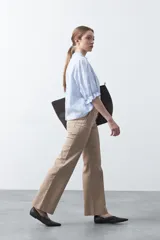 Pantalón negro de tiro alto, corte recto y silueta clásica. Presenta costuras verticales marcadas en la parte delantera de las piernas.