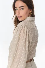 Camisa marrón con estampado de flores blancas, de corte cropped con nudo frontal y mangas largas abullonadas.