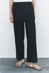 Pantalón color beige de corte ancho, con tiro medio, trabillas en la cintura y raya planchada.