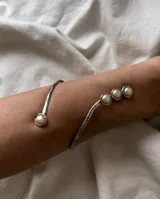 Brazalete hecho a mano en alpaca o bronce, con diseño minimalista y perlas.