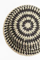 Sombrero tipo bucket de paja trenzada en colores beige y negro, con diseño calado.