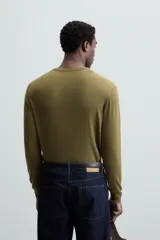 Jersey negro de lana con acabado mercerizado, corte relaxed fit, cuello redondo y mangas largas con terminaciones en rib.