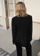 Blazer negro de corte recto, con cuello de pico cruzado y cierre de un solo botón. Presenta solapas con muesca, bolsillo de ribete en el pecho y dos bolsillos de solapa laterales.