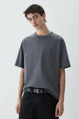 Remera gris de punto pesado con cuello redondo ribeteado, hombros caídos y bajo recto. Corte holgado confeccionada con tejido funcional COOLMAX®, una fibra exclusiva de poliéster de secado rápido que elimina la humedad y regula la temperatura corporal.