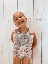 Traje de baño entero para niña con estampado floral y volados en los hombros.