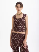 Musculosa de punto color marrón con estampado de cadenas y labios en forma de rombos. Presenta escote cuadrado y corte ajustado al cuerpo.