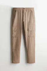 Pantalón cargo color beige de corte recto, con cintura elástica ajustable con cordón, bolsillos laterales con cierre, bolsillos tipo cargo con solapa en los laterales y bolsillos traseros insertados.