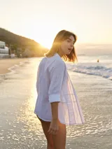 Camisa negra de lino con corte femenino, cuello clásico, cierre frontal con botones y mangas 3/4 con puños. Presenta detalles de frunces en el frente.