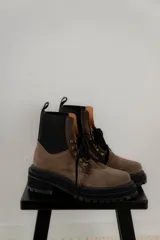 Borcego de gamuza color verde militar con elásticos laterales negros, cordones negros y suela de goma negra con plataforma.