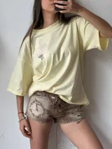 Short de jean color marrón claro con efecto desgastado, tiro alto, cierre con cordones cruzados y detalles rotos.