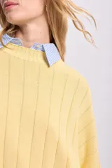Sweater de punto tejido color amarillo, de corte holgado y cuello alto.