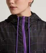Campera cropped con capucha, de poliéster color negro con estampado de cuadros y salpicaduras de colores. Tiene cordón de ajuste en la capucha, elástico en puños y ruedo, bolsillos con cremallera y cierre frontal con cremallera.