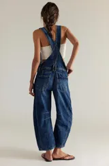 Overol de denim azul con tirantes ajustables, bolsillos frontales y traseros, y corte recto.