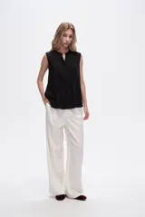 Blusa viscosa color negro, corte evasé, sin mangas, con cuello a la base y botón en la parte superior.