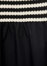 Vestido midi de punto a rayas horizontales negras y crudas, con cuerpo ajustado sin mangas y falda amplia de algodón color negro.