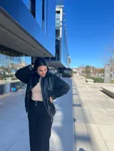 Chaqueta bomber negra con paneles de cuero en la parte delantera y mangas, y tejido texturizado en el resto del cuerpo.
